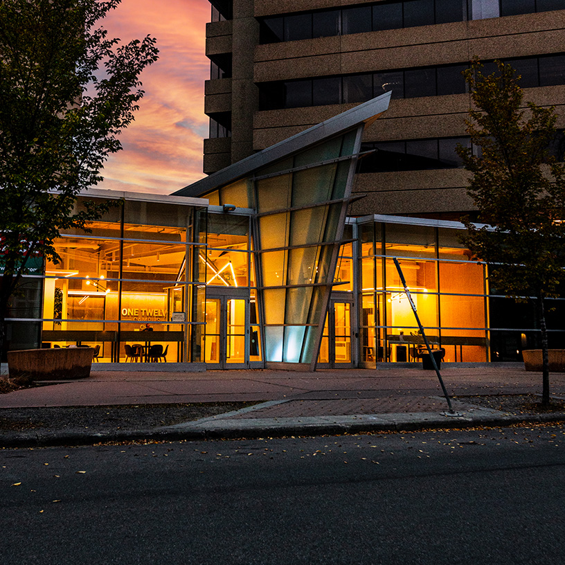 One Twelve Campus entrance at night with glowing interior.