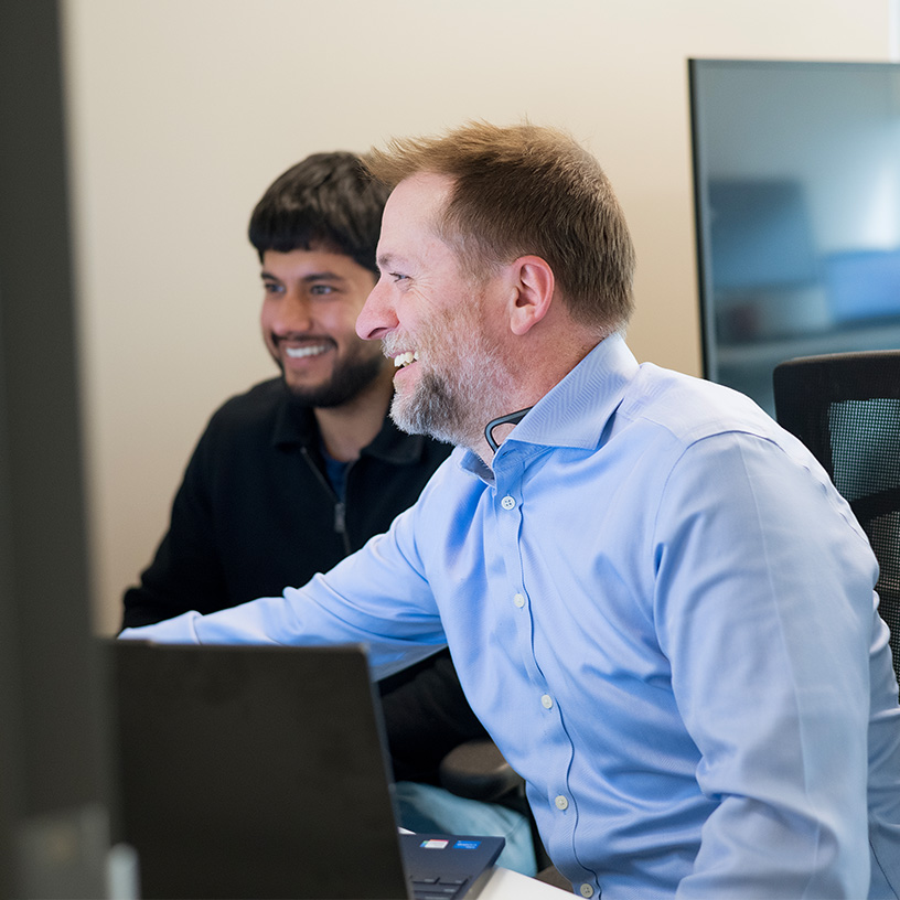 Two people smiling while working at a desk