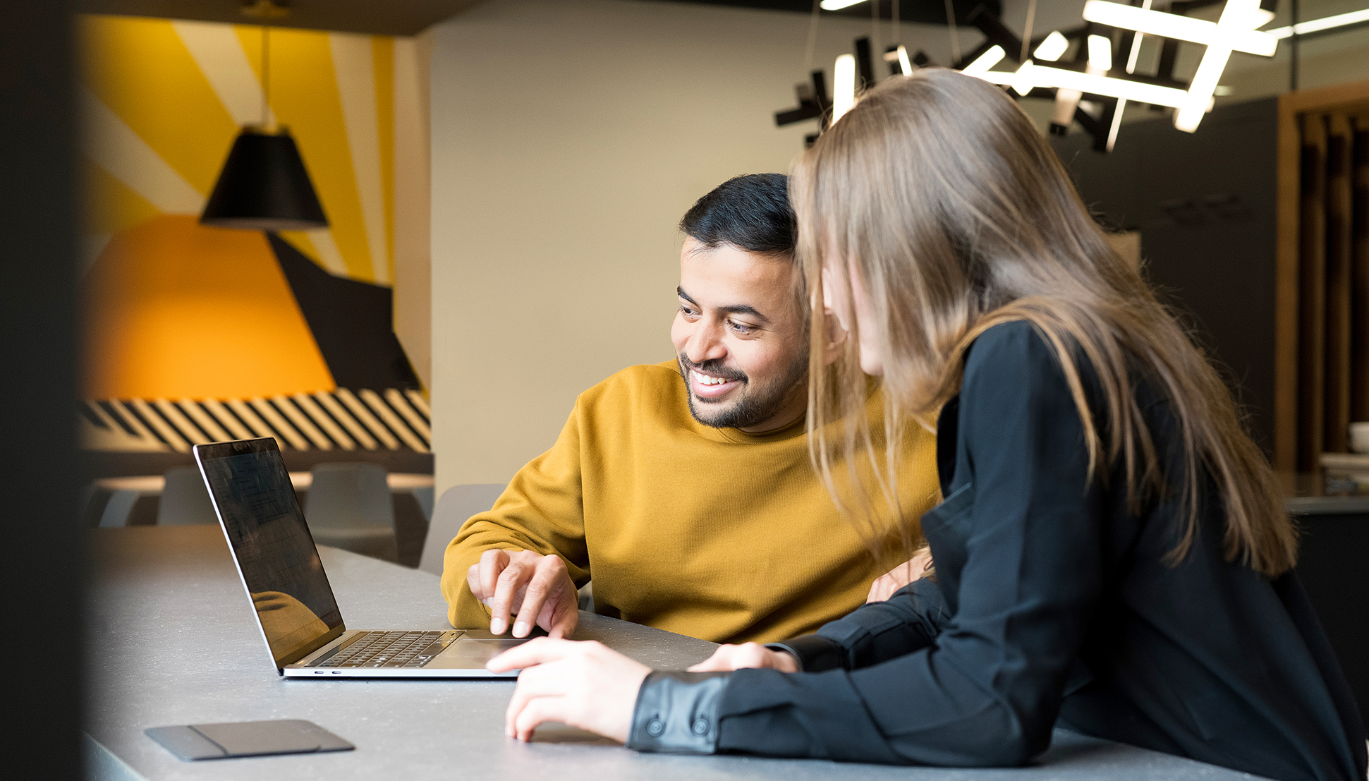 Two people working on laptop.