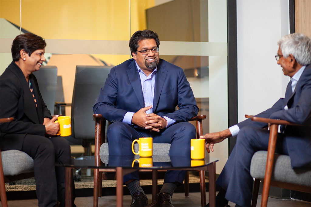 Rohit, Krishna and Radhe sitting in chairs with smiles and drinking from coffee mugs.