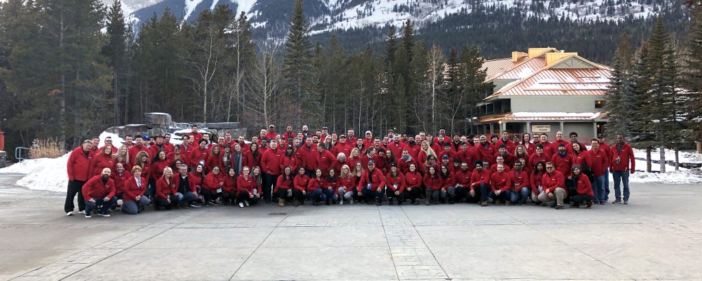 Wide angle photo of Rohit team all wearing read jackets at an outdoor winter retreat.